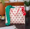 large rectangular bag with a cherry pattern on a light pink background filled with clothes