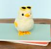 A fluffy yellow wind-up duck toy wearing yellow sunglasses