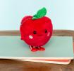 Red apple-shaped plush wind-up toy with a smiling face and a green leave on top