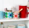 Mini daisy tins repurposed as kitchen storage on a shelf.