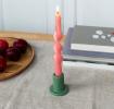 Khaki ceramic candle holder with a cylindrical shape and wide flat base, holding a lit pink candle