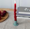 grey ceramic candle holder with a cylindrical shape and wide flat base, holding a lit red candle
