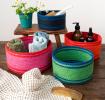 Four woven storage baskets in varying sizes and colours