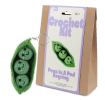 Crochet kit packaging placed beside finished green peas in a pod keychain 