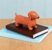 Squeezy squishy toy shaped like a brown sausage dog with floppy ears and a cute face placed on the book.