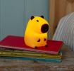 Yellow capybara night light with dark brown ears, nose and feet shown with light on