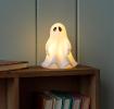 White ghost night light with black eyes, with its light turned on