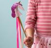 Kid holding pink unicorn wand with glittery top and ribbon streamers