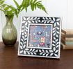 Square picture frame with white leaf patterns and navy blue colour on the border.