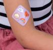 Plaster applied to a kid's arm with a kawaii sunshine-themed design.