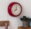 Round red wall clock with black hands and numbers,