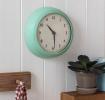 Round mint green wall clock with black hands and numbers