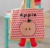 Yellow handbag with red polka dots and a cartoon apple design with two red feet at the bottom