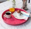 Round enamel trinket tray in vibrant pink displayed with cup of coffee, orange juice and egg.