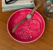 Vibrant pink enamel trinket dish displayed with a wristwatch and jewellery 