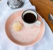 enamel trinket dish in soft pink displayed with a cup of black coffee and biscuit.