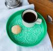 enamel trinket dish in green displayed with a cup of coffee and biscuit.