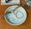 enamel trinket dish in light grey displayed with a watch and jewellery