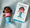 Mini mermaid soft toy placed beside a small illustrated box with mermaid design
