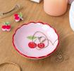 round ceramic trinket dish with scalloped red edge and cherry design in the center