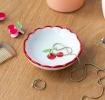 Round ceramic trinket dish with scalloped red edge and cherry design in the center.