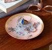Round trinket dish with gold rim, pink background, palm tree pattern, and a leopard face design