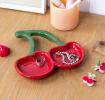 Red ceramic trinket dish shaped like two cherries with green stems displayed with ring and bracelet. 