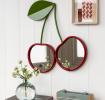Wall mirror shaped like two cherries with red frames and green leaf detail hanging on the wall.