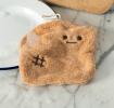 Brown kitchen cloth shaped like a slice of bread with embroidered face and hanging loop