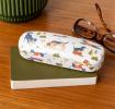 glasses case with playful dog illustrations resting on a notebook beside a pair of glasses.