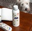 Stainless steel bottle with playful dog illustrations on a table beside a matching glasses case.