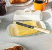 Rectangular white enamel butter dish with a pistachio green rim and a handled lid displayed with butter.