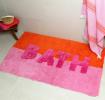 An orange and pink tufted bath mat with the word “BATH” in bold letters.