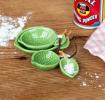 Set of four ceramic measuring spoons shaped like green leaves with brown stem handles 