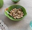 Green ceramic bowl with textured surface and a leaf design near the rim with brown stem accent