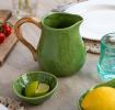 Green ceramic jug with textured surface and a curved brown handle