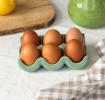 Green ceramic egg holder displayed with six eggs. 