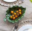 Green ceramic leaf-shaped trinket dish displayes with yellow tomatoes