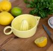 A yellow ceramic lemon juicer shown with sliced lemons.