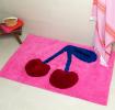 A pink tufted bath mat featuring a cherry motif.