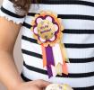 An “It’s My Birthday” badge attached to a child holding a wrapped gift.