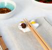 Chopsticks resting on a ceramic cat–shaped chopstick rest.