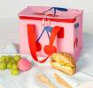 A cherry‑themed insulated lunch bag placed on a table next to fruit.