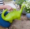 An green dinosaur‑shaped watering can held outdoors.