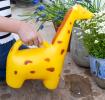 A yellow giraffe‑shaped watering can placed on a patio near plants.