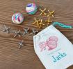Traditional jacks set with drawstring bag, two striped balls, and gold and silver jacks.