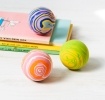 Three colourful bouncy balls in pink, purple and green with swirling patterns.