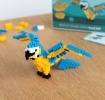 Completed macaw brick model displayed beside its packaging box.