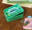 Green mini storage tin with a tuna illustration on the front.