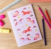 Pink notebook with colourful unicorns, rainbows, stars, and suns on the cover.
